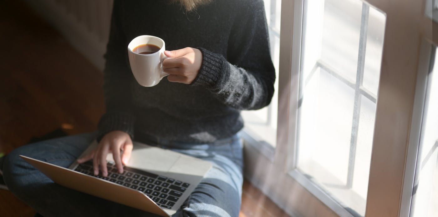 A person resting quietly with coffee by a window